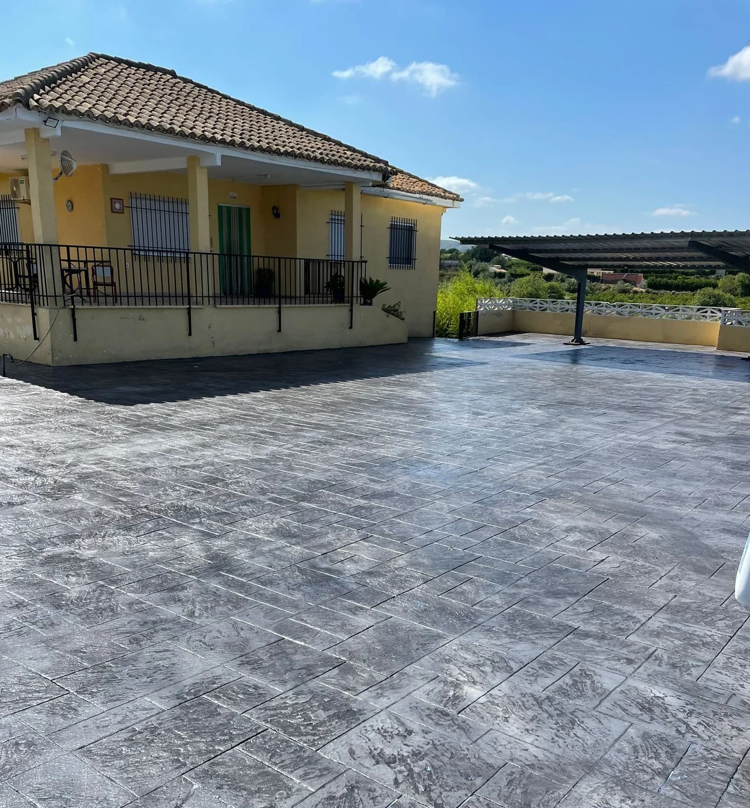 Patio de una vivienda en urbanización pavimentado con piedra inglesa en gris medio