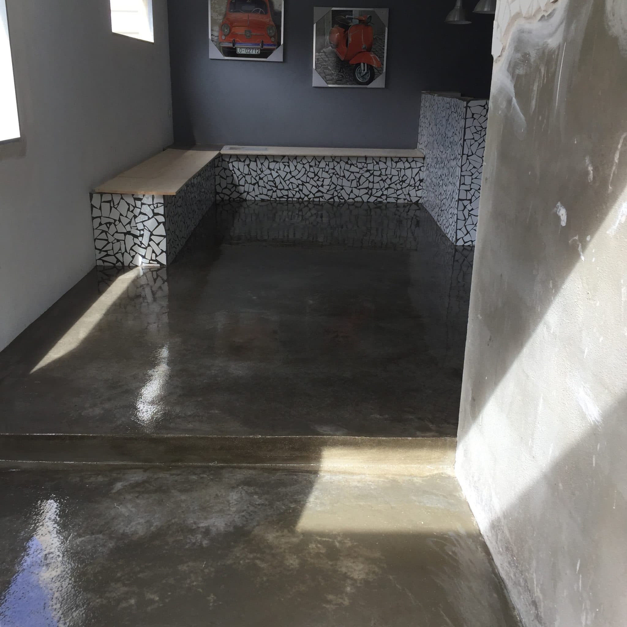 Interior con suelo de hormigón pulido brillante que refleja la luz de las ventanas